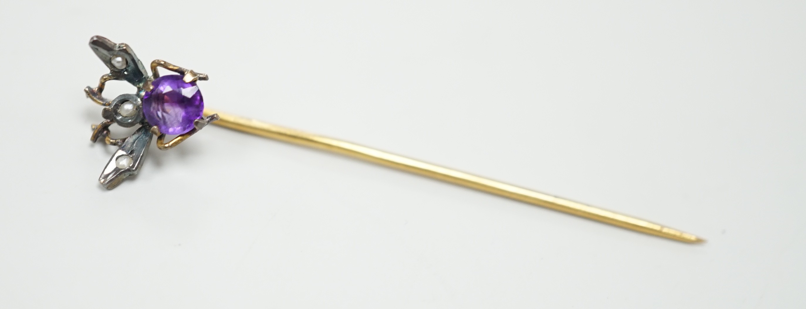 An early 20th century yellow and white metal amethyst and seed pearl set bug stick pin, 4mm, gross weight 0.6 grams.